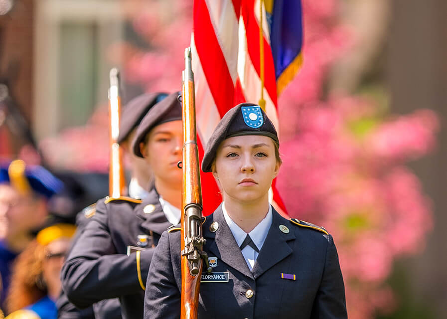 A military science student marches with a color guard.