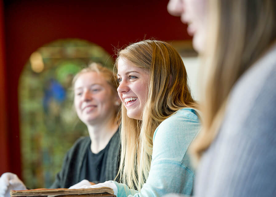 Classical studies student smiling while holding historical textbook