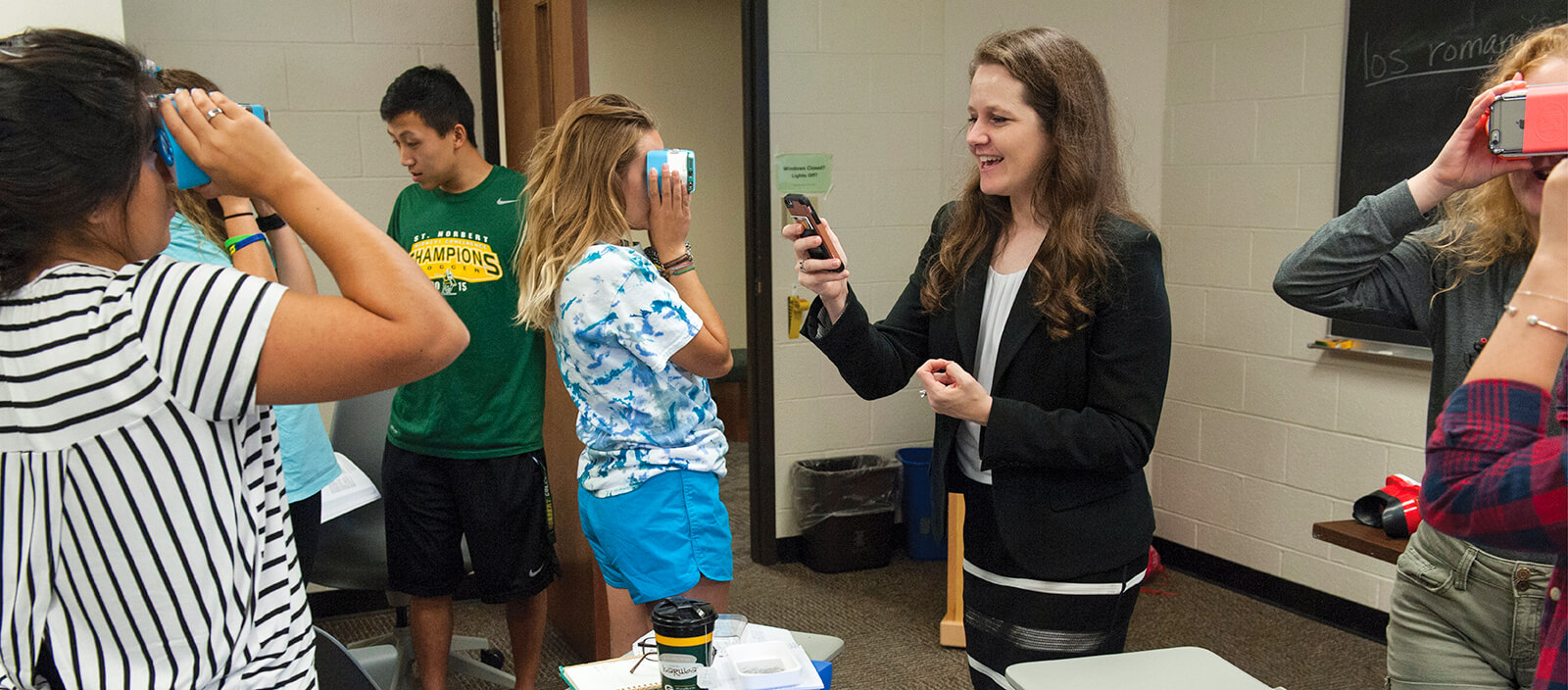 Professor Katie Ginsbach holding a mobile device as part of a teaching exercise.