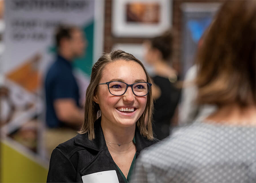 Student smiles while talking to a prospective employer at a career fair on campus