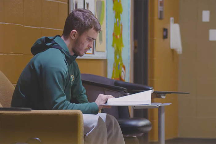 Ben Berg reading a text book in an academic building on campus