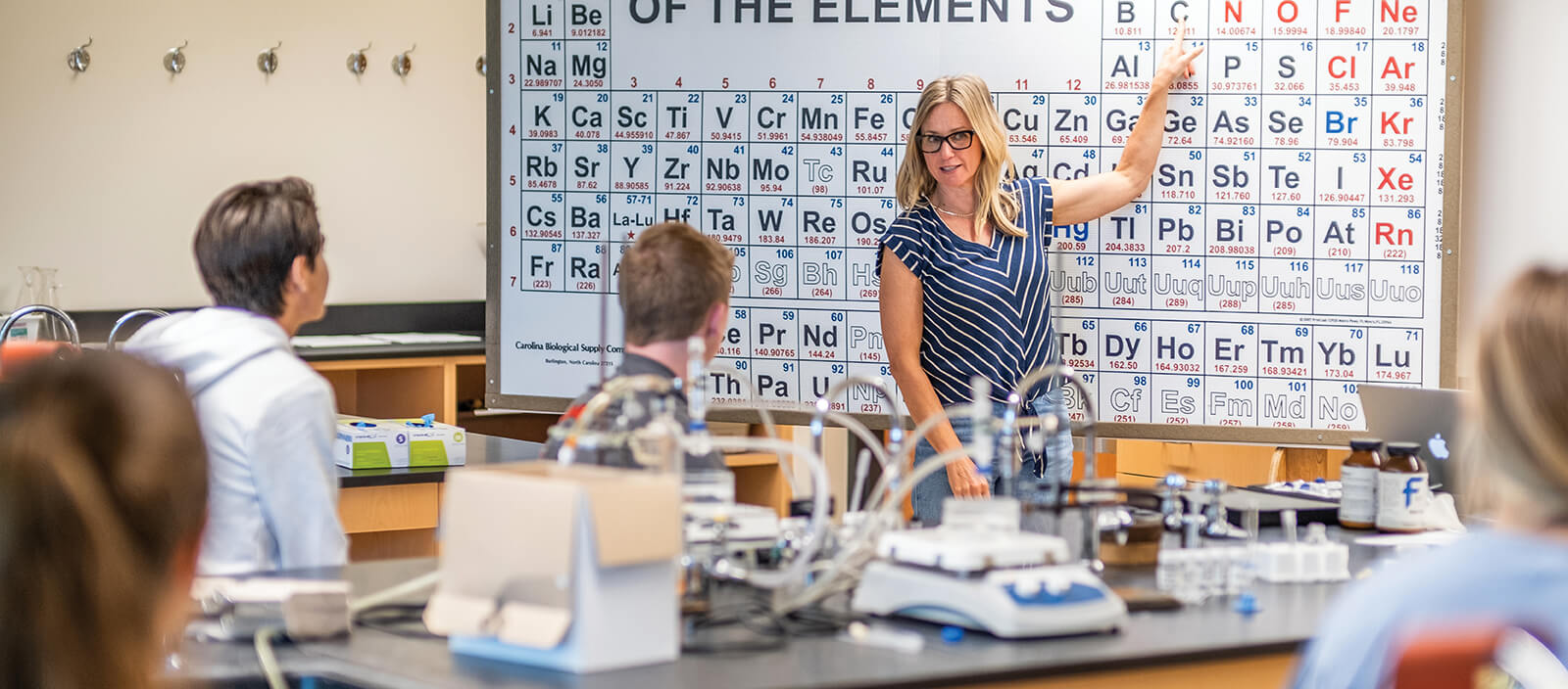 Professor Cyndi Oschner teaching in front of a periodic table