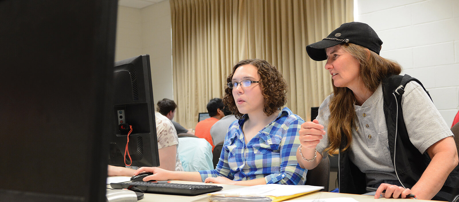 Professor Bonnie McVey sitting with a student at a computer