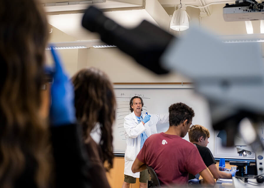 Student wearing lab coat works with test tubes in a biology lab