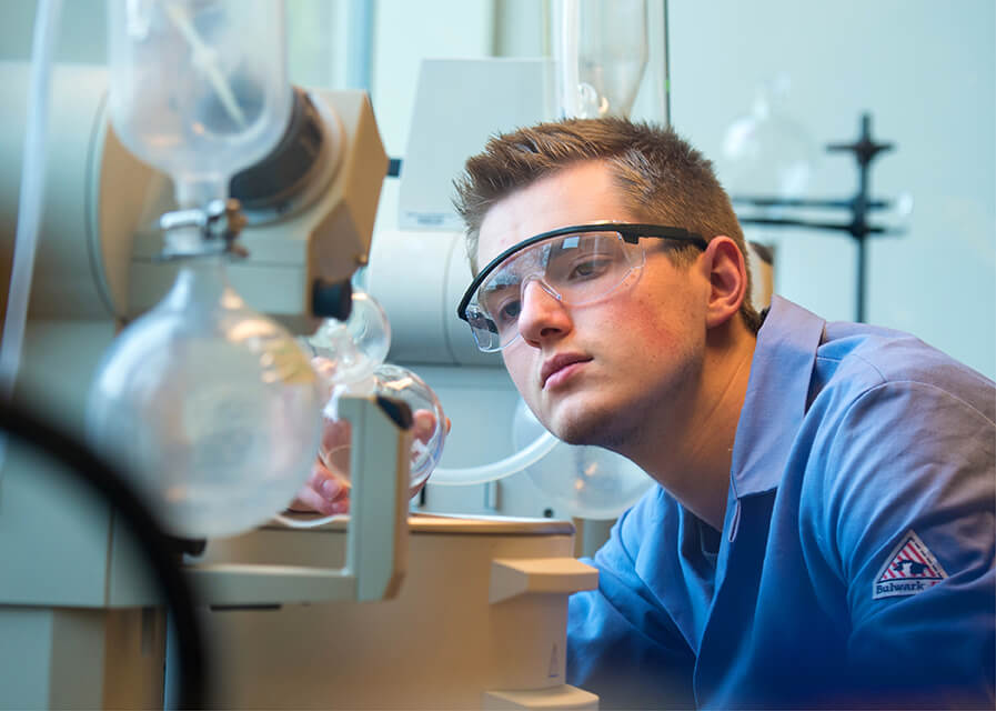 Two students wearing medical scrubs inspect model bones