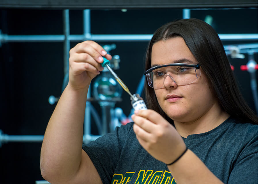 A student examines a test tube while working in the lab.