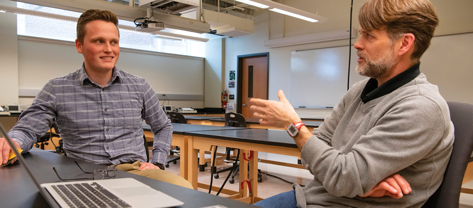 A student and a professor have a conversation in a science lab.