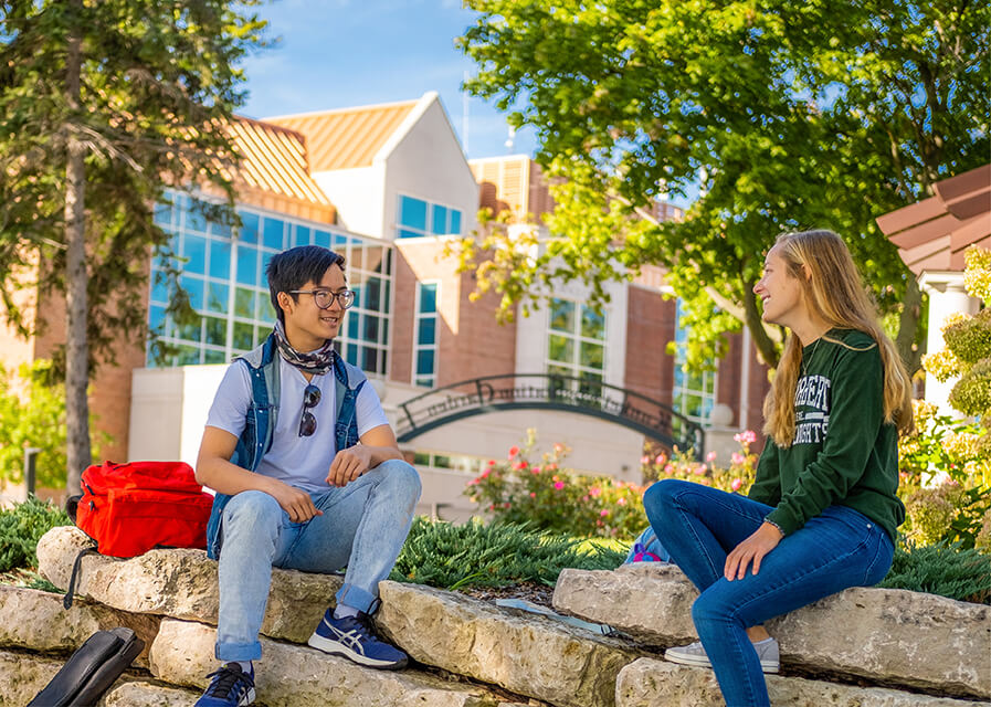 Two students talk to one another outside on the St. Norbert College campus.