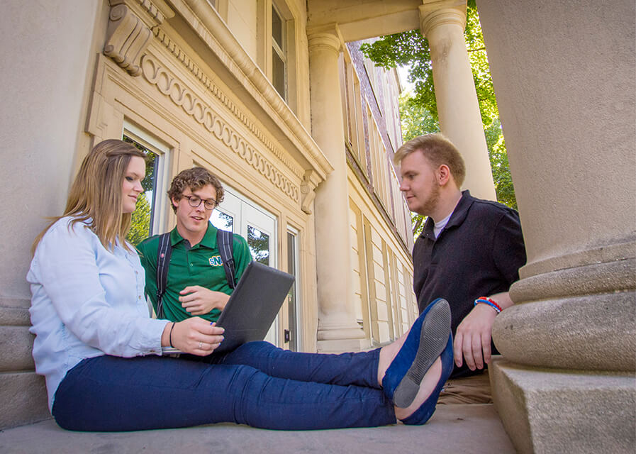 Pre-law students work on a laptop while sitting on the steps of Boyle Hall at SNC.