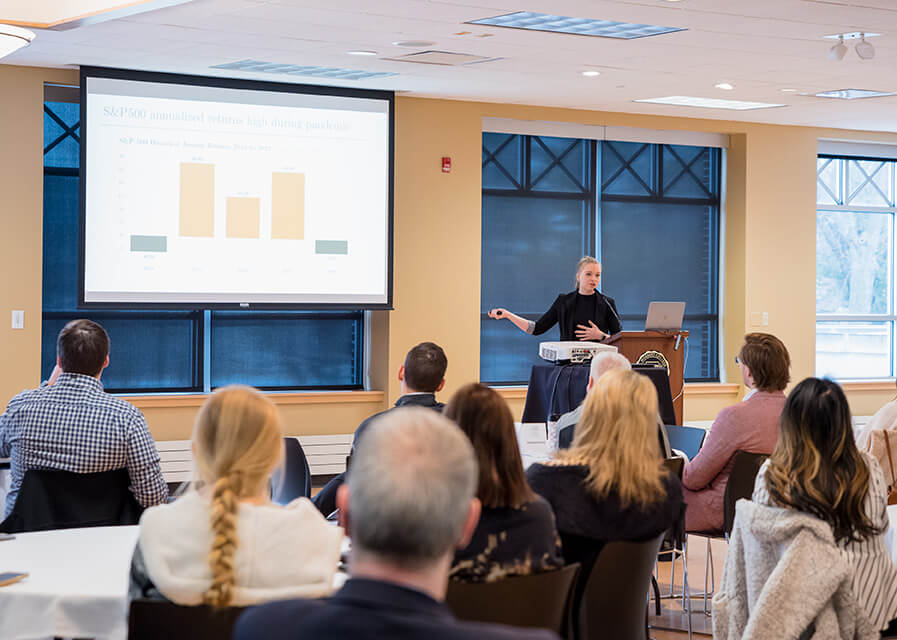 Two female students present to a room of area professionals.