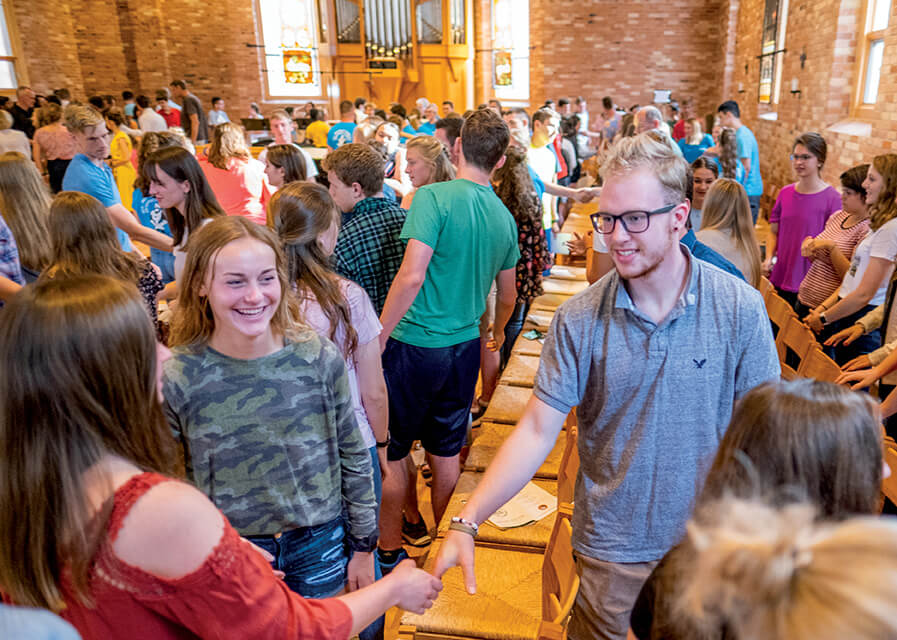 Students shaking hands and smiling during a church service at St. Joseph's 
