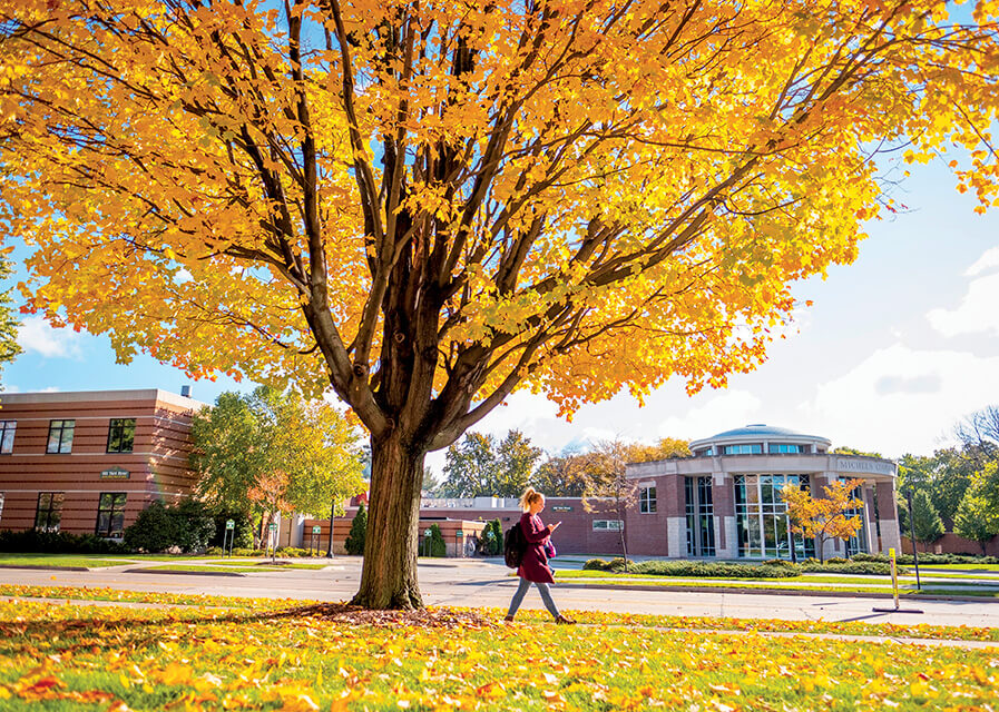 Shot of Michels Commons in the fall with a student walking by