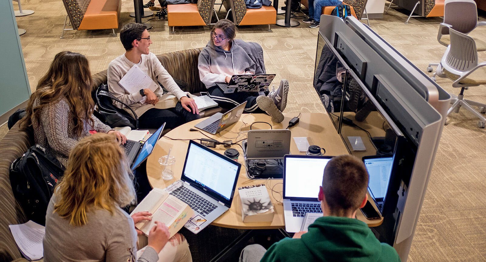 Students sit around a table and work on a project