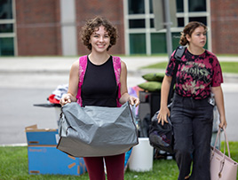 Student carries belongings into a campus residence hall