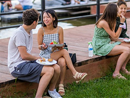 Students sit on the docks and enjoy food and each other's company