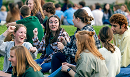 A group of students sits outside on campus at SNC.