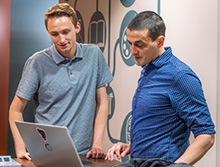 a students works at a computer with a professor