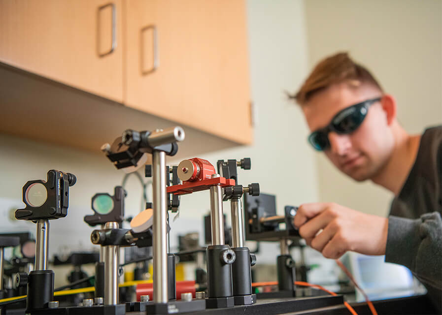 A physics student demonstrates part of a research project.