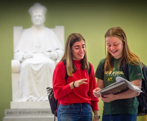 SNC students with a statue of Abbot Pennings in the background