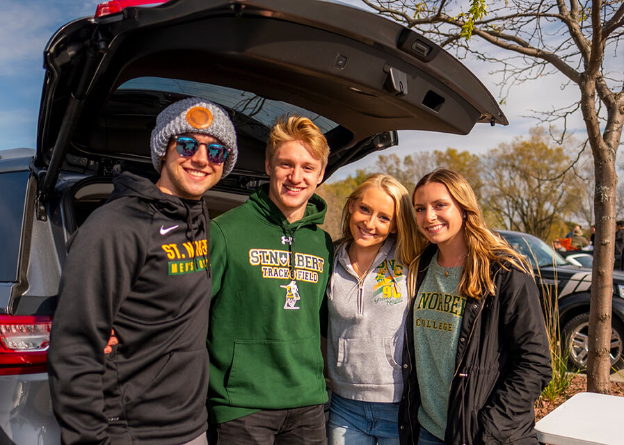 Students pose behind a car at the parking lot