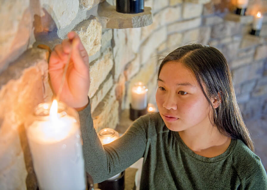 Student lighting a candle at the grotto