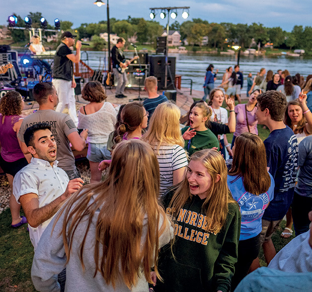 Students dance while listening to a band play by the Fox River.
